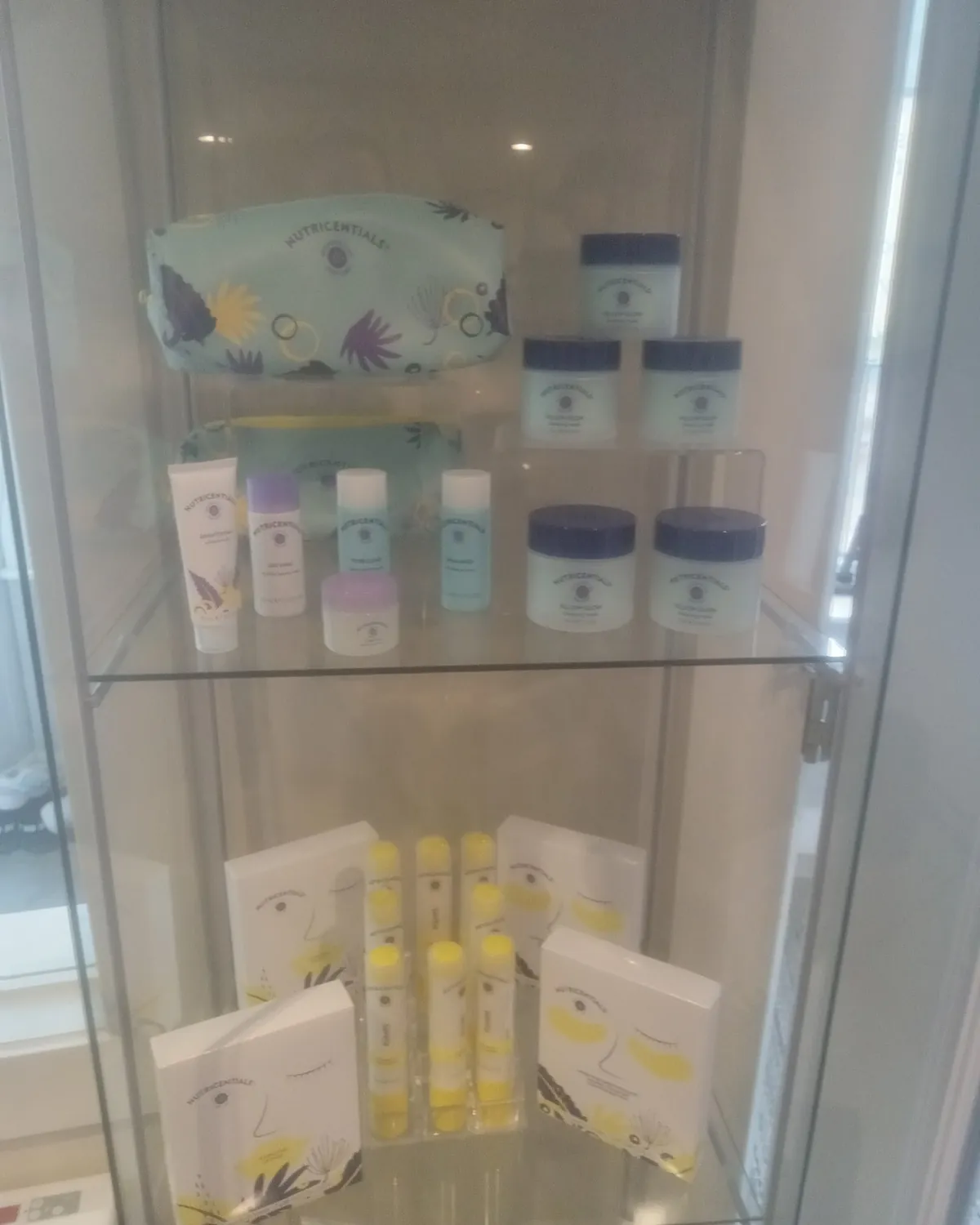 Glass display case with jars, tubes and a floral bag inside Renew You