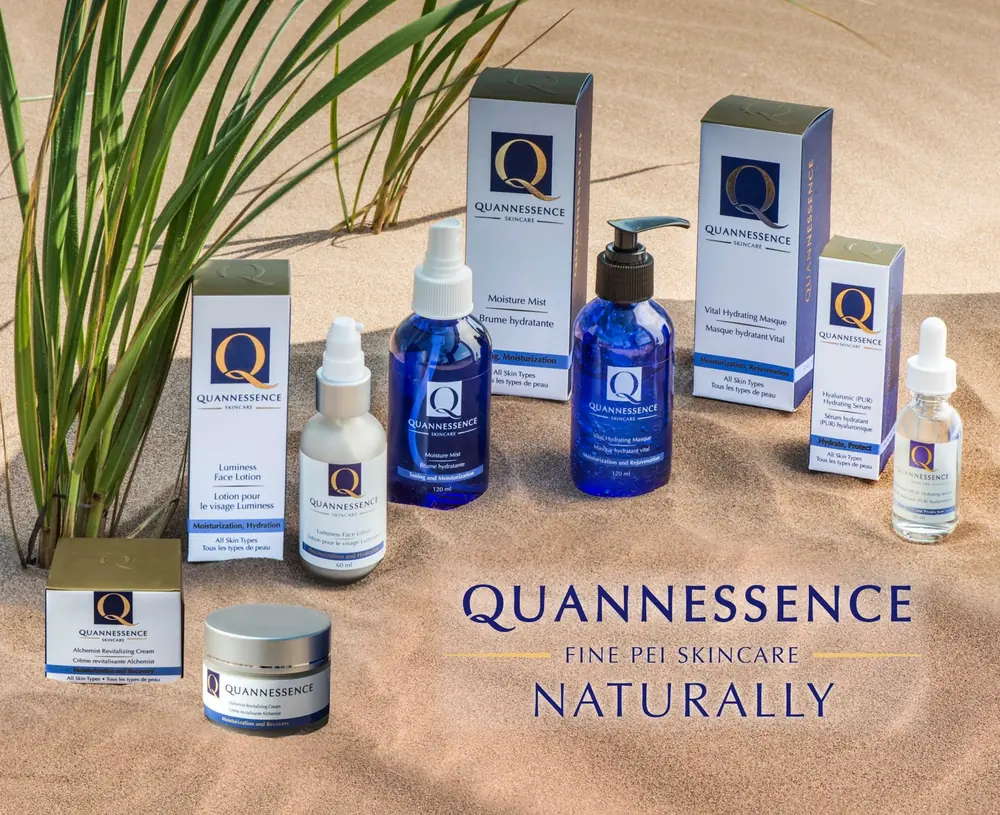 Quannessence skin-care bottles and boxes on sand with grasses