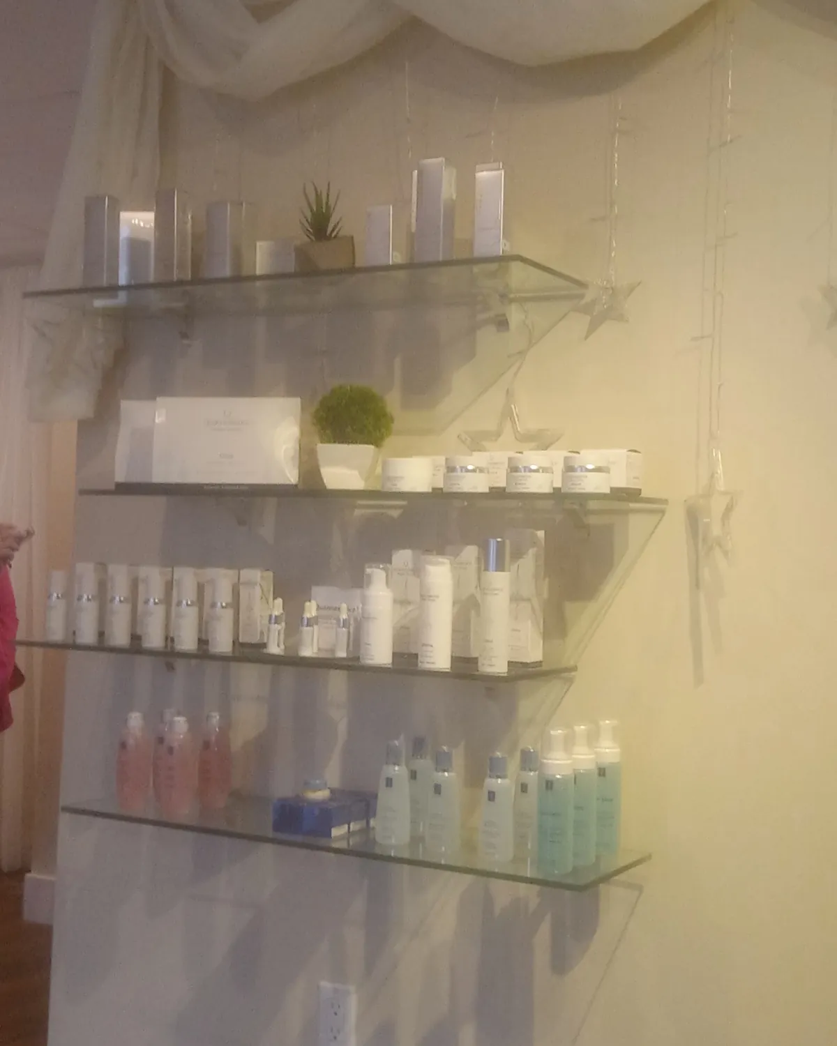 Glass salon shelves holding white skin-care bottles